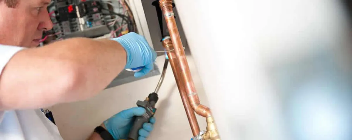 Water heater repair technician testing copper pipe connections and controls in Detroit, MI